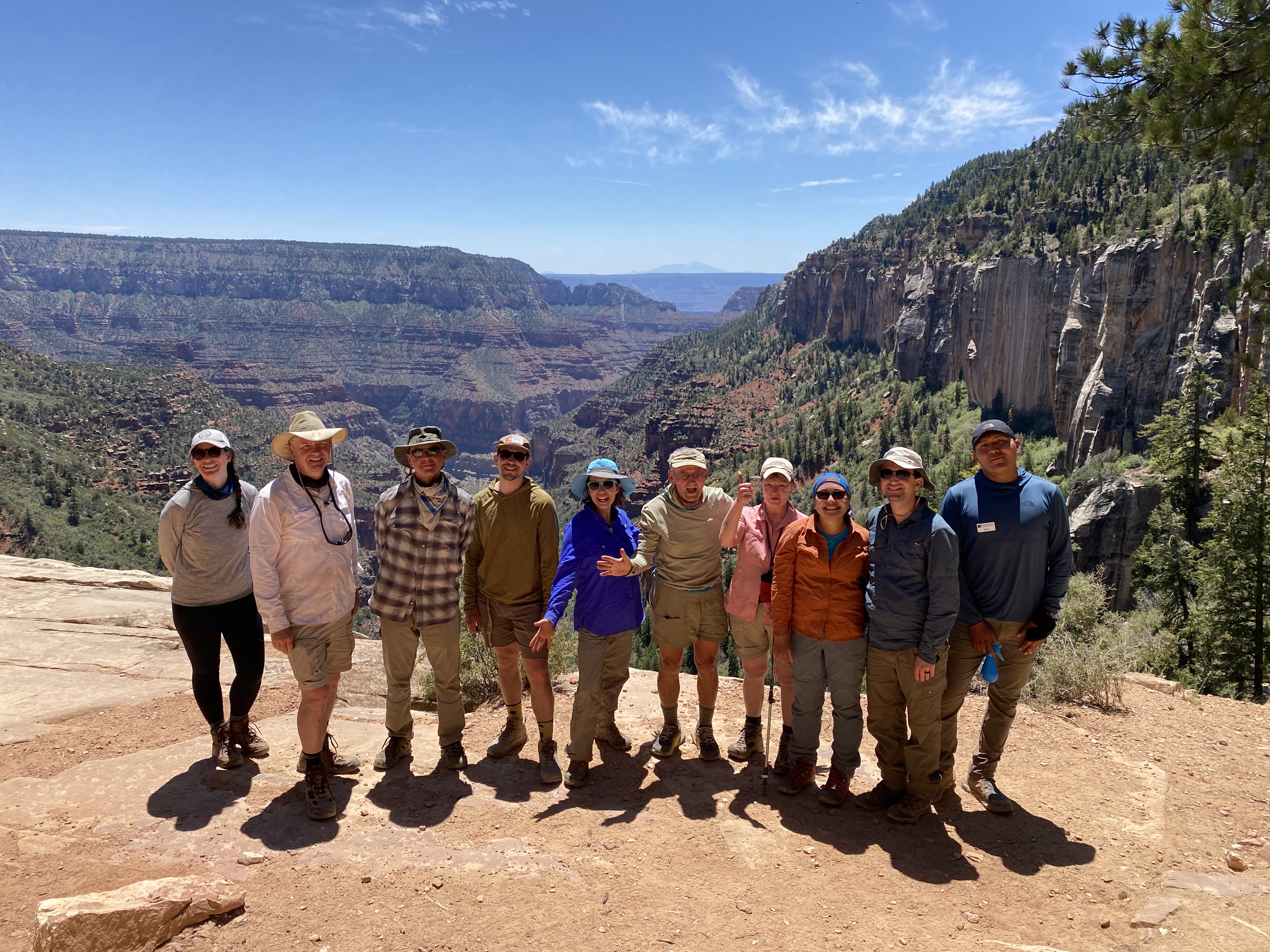 Group of hiker tourists with Field Institute tour guide standing smiling in bright daylight at Grand Canyon on hike