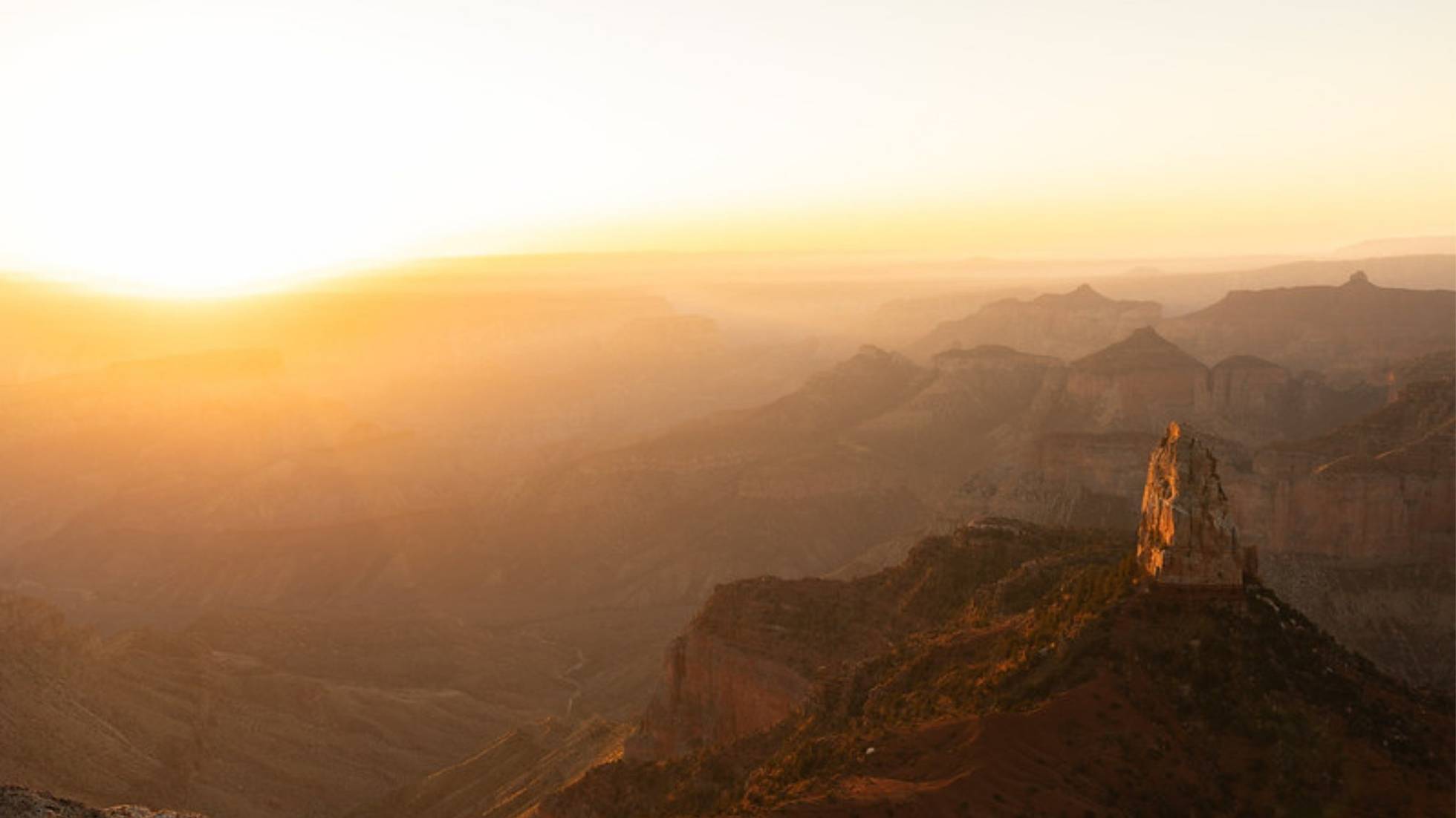 Sunrise lighting Grand Canyon ridges and a tall butte