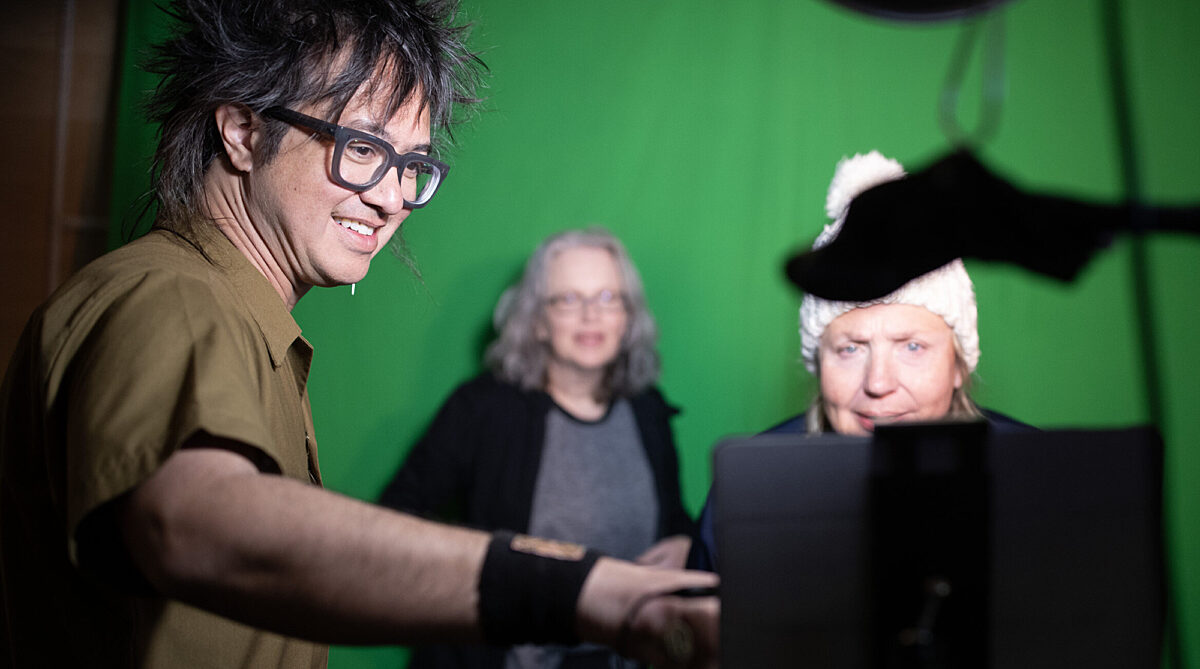 sTo Len Artist in Residence shows something to a visitor on a screen