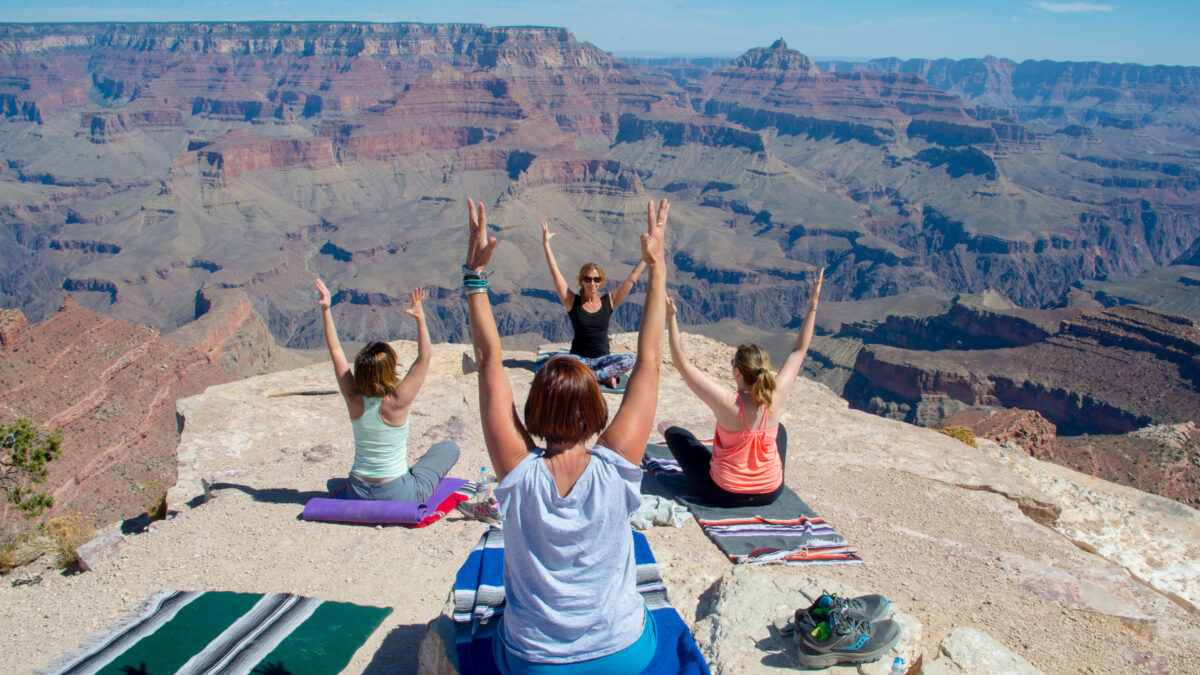 Four women in a seated yoga pose along Grand Canyon's rim
