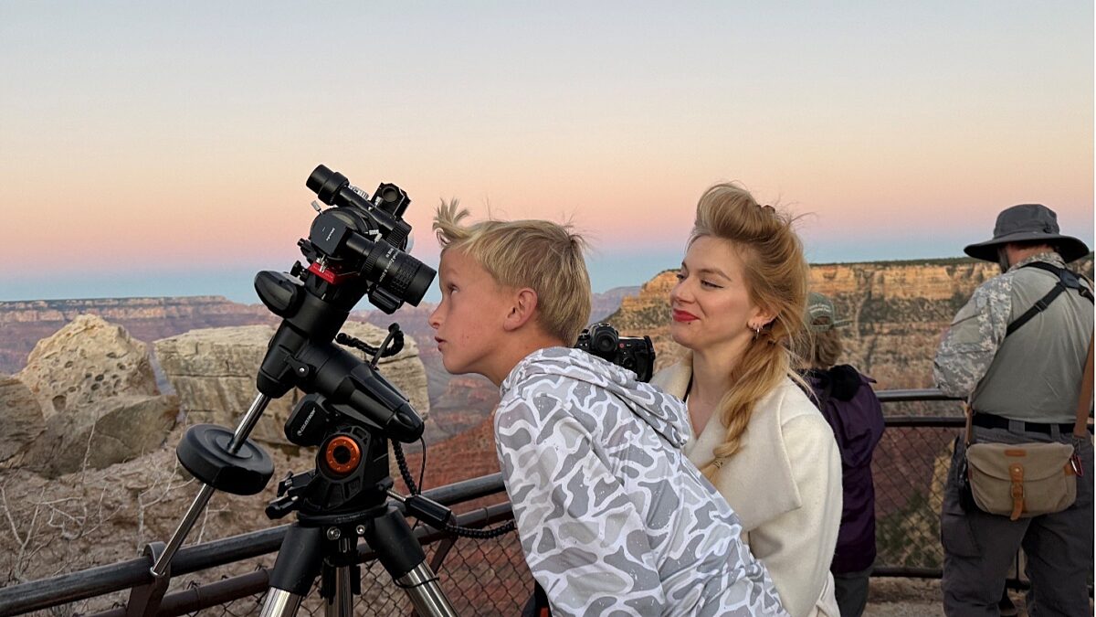 Young boy looking into a telescope at Grand Canyon with a woman guiding him