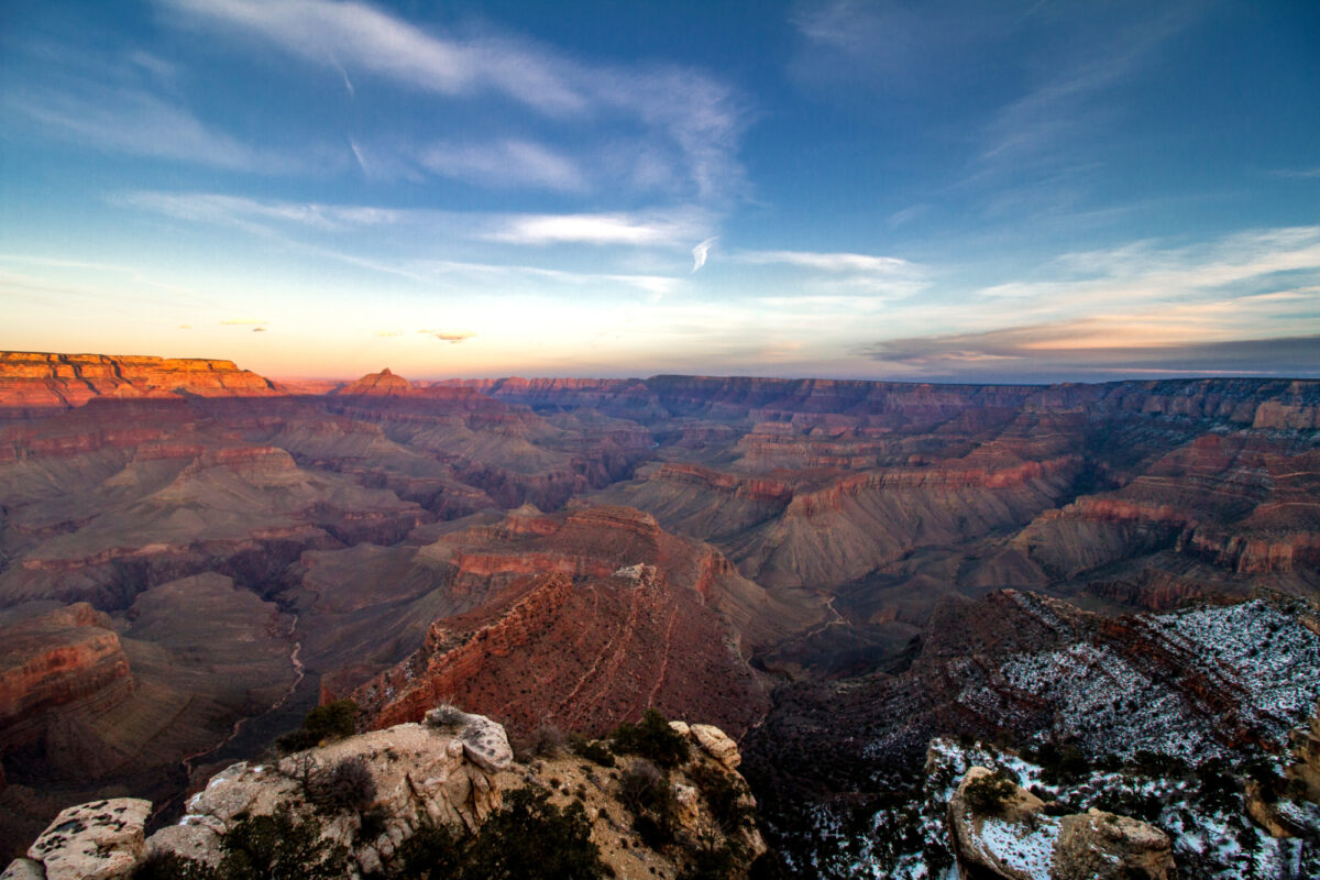 Aerial view of evening sun casting on Grand Canyon with snow covered rocks in forefront