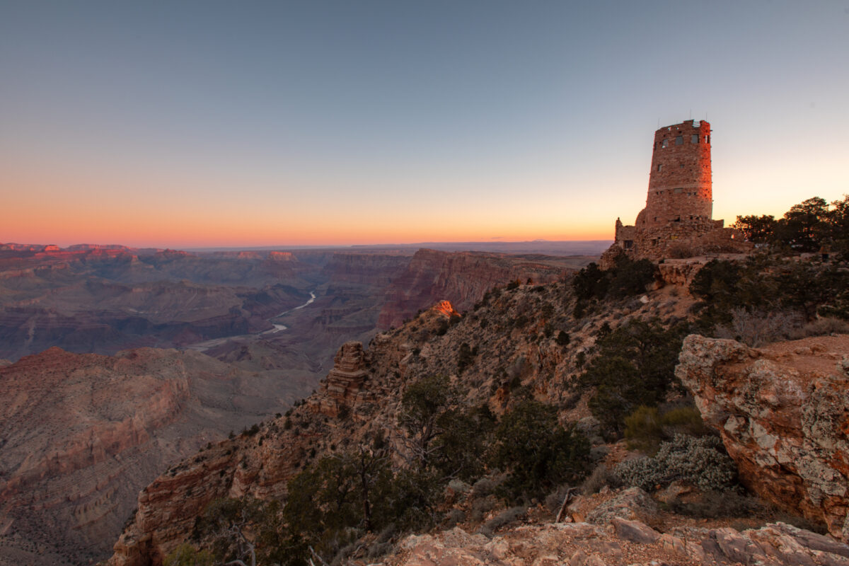 Panoramic wide view of Grand Canyon with red sunset and Desert View Watchtower on right side