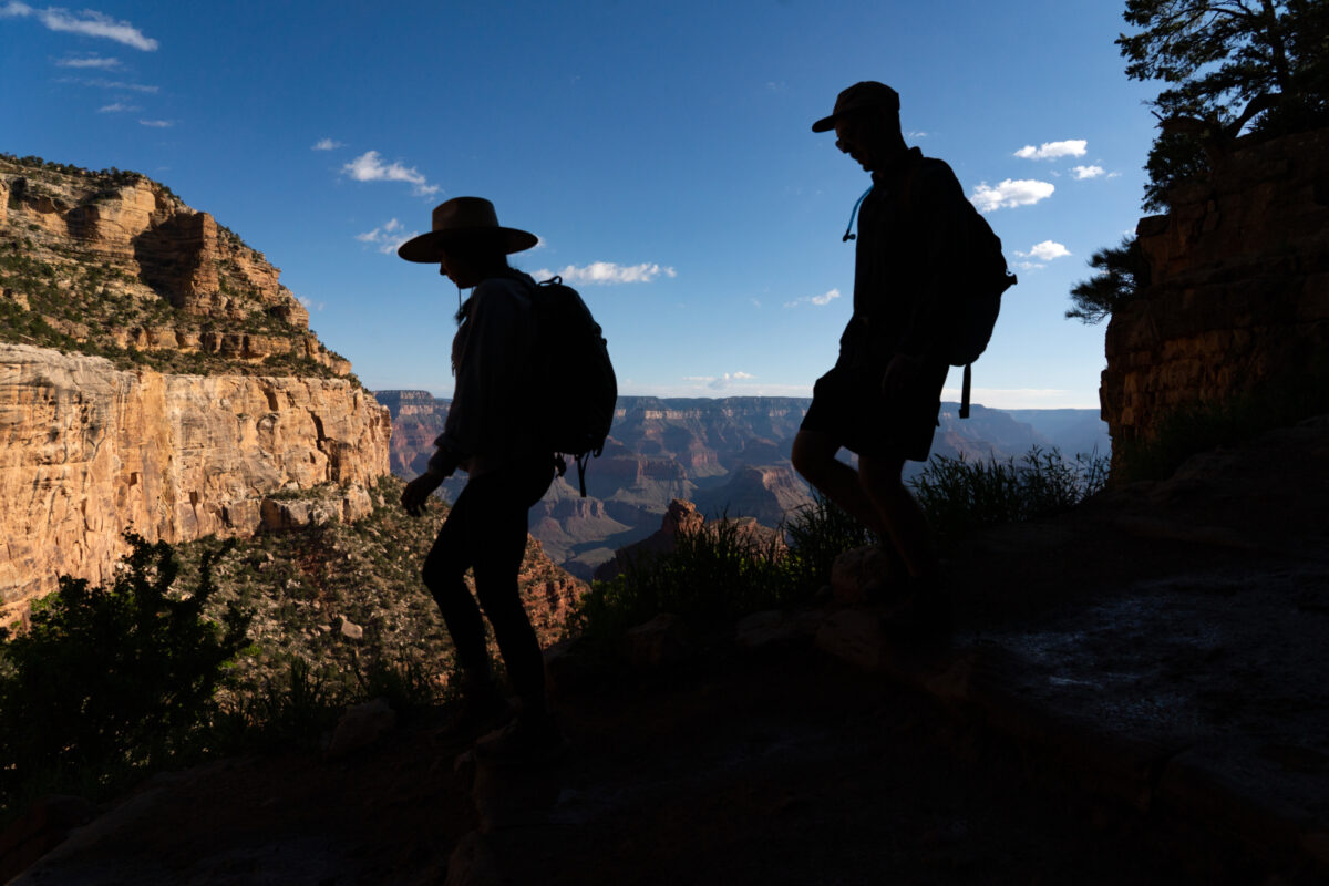 Two silhouetted figures hike down a trail PC David Wallace