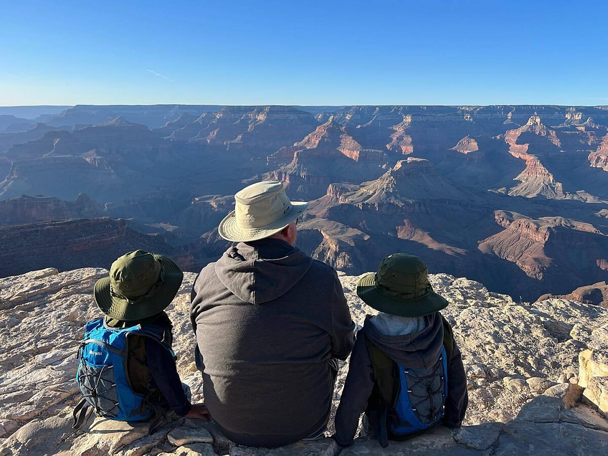 A dad and his two sons gaze out and take in the beauty of grand canyon.