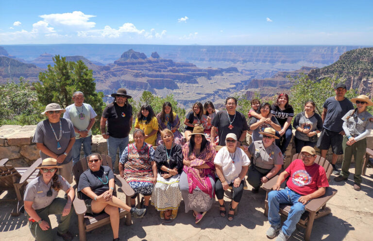Participants of the North Rim Heritage Days 2022 stand and sit on the veranda outside of the North Rim Lodge.