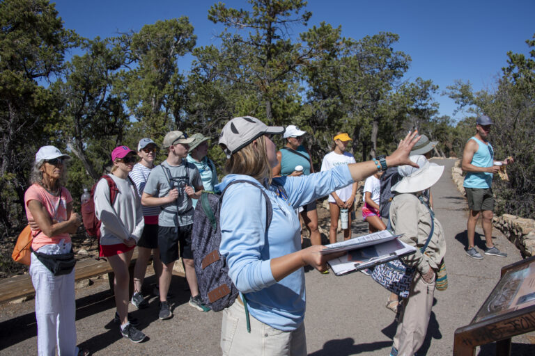 guide points to the right while a crowd looks in that direction