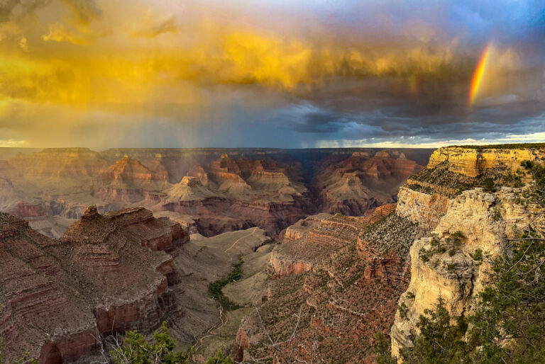 Sunset near Grand Canyon Village. Colors of yellows and blues can be seen and a rainbow.