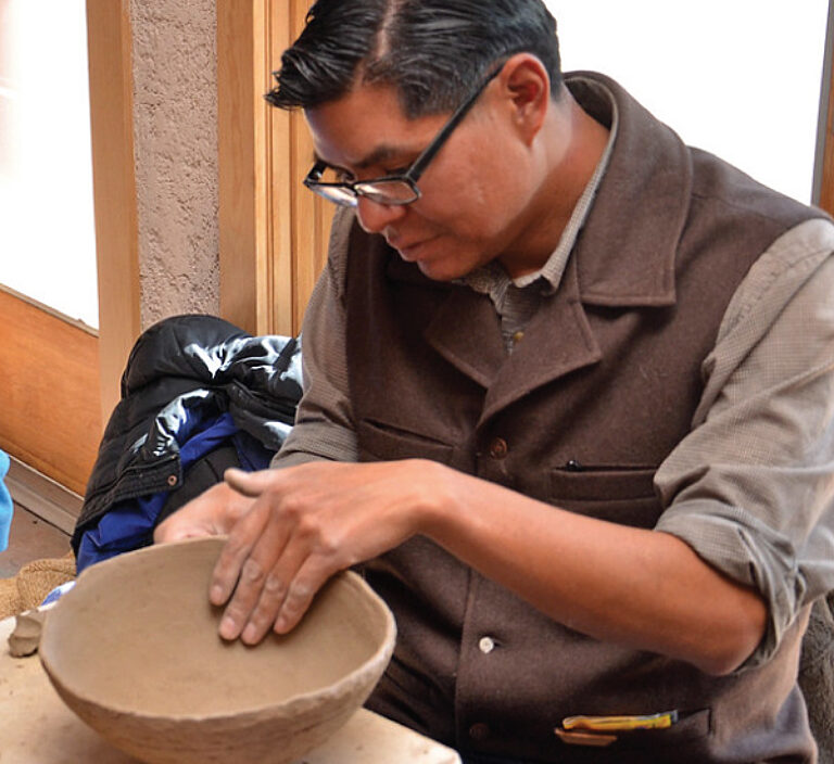 Person at table working clay pottery
