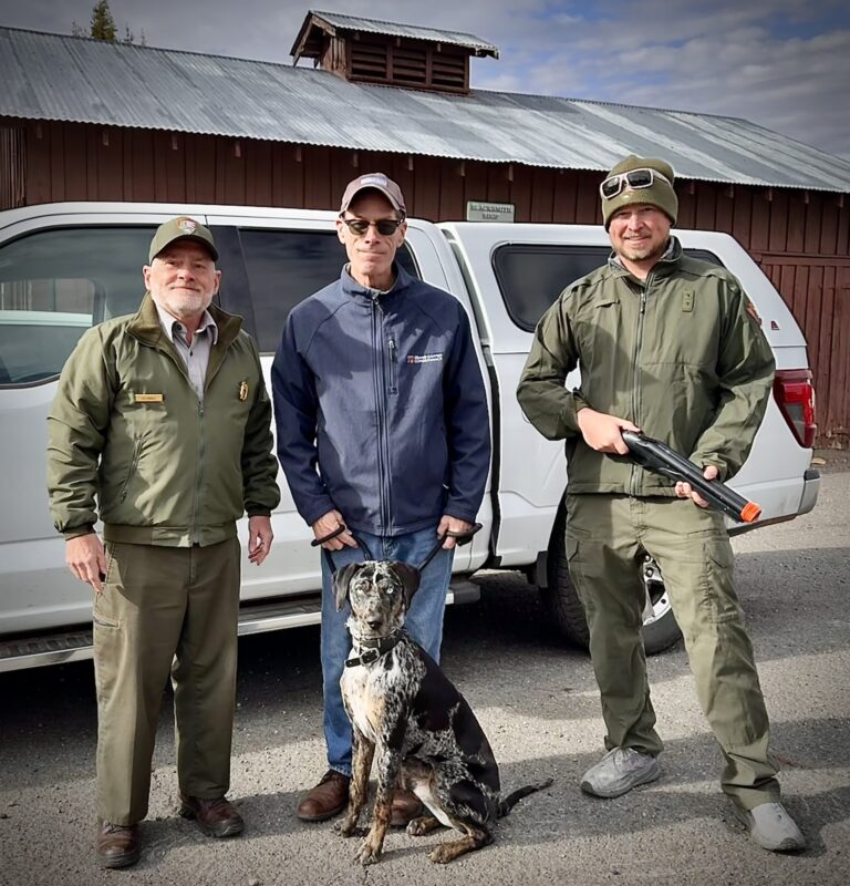 Superintendent Ed Keable on left, husband Scott in the middle with the K9 Blue sitting in front of him, and wildlife biologist, Houston on the right.