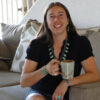 Carrie Cannon seated on couch smiling holding mug