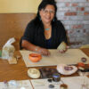 Eileen Yatsattie smiling while molding clay sculpture