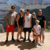 Family of 5 standing and smiling for photo on rock edge at Grand Canyon