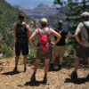 Five hikers standing on forest cliff edge overlooking Grand Canyon 2017