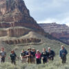 Group of hikers standing and smiling in front of canyon from ground level at Grand Canyon