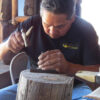 Jonathan Mike crafting silver piece with hammer on wooden stump