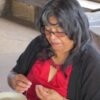 Margia Simplicio working holding bead and thread seated