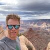 Dr. Cameron takes a selfie with sunglasses on and the Grand Canyon in the background.
