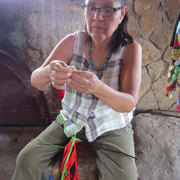 Darnell Lewis seated on rock seating weaving with fingers