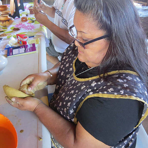 Dorothy Ami working on clay pot sitting at table