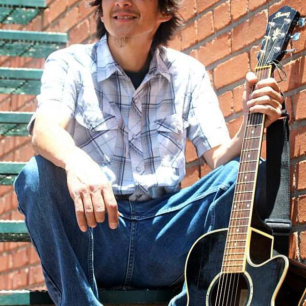 Ed Kabotie holding guitar smiling off in distance