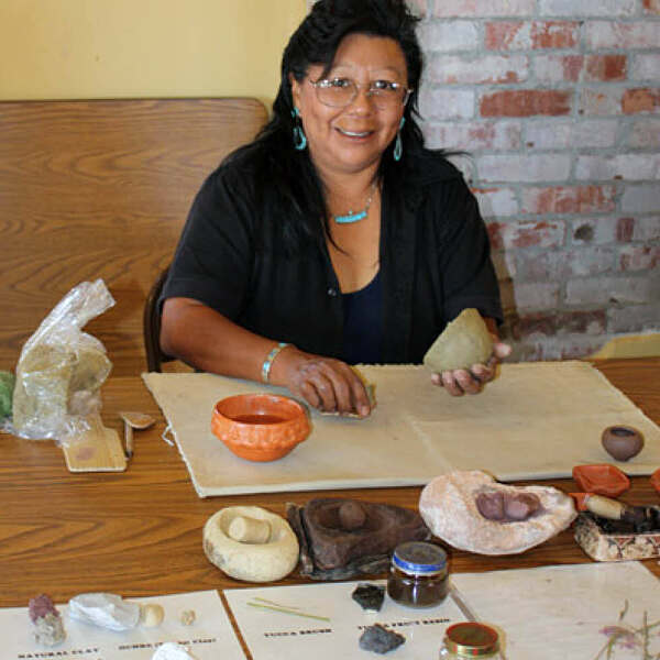Eileen Yatsattie smiling while molding clay sculpture