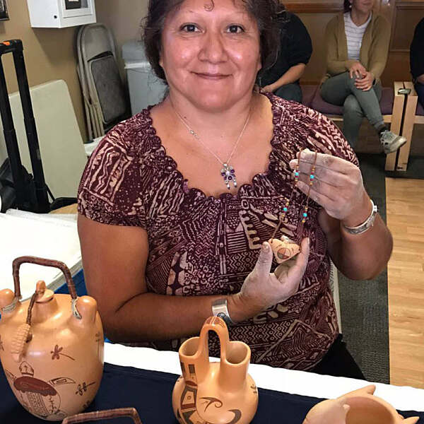 Gwen Setalla smiling holding clay necklace piece