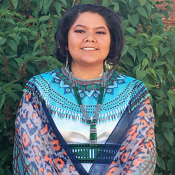 Janelle Powskey standing in traditional dress smiling