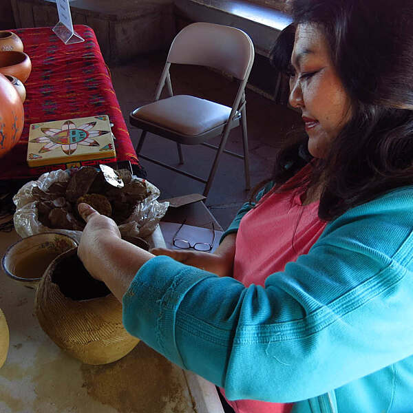 Renee Archambeau smiling while shaping clay pottery